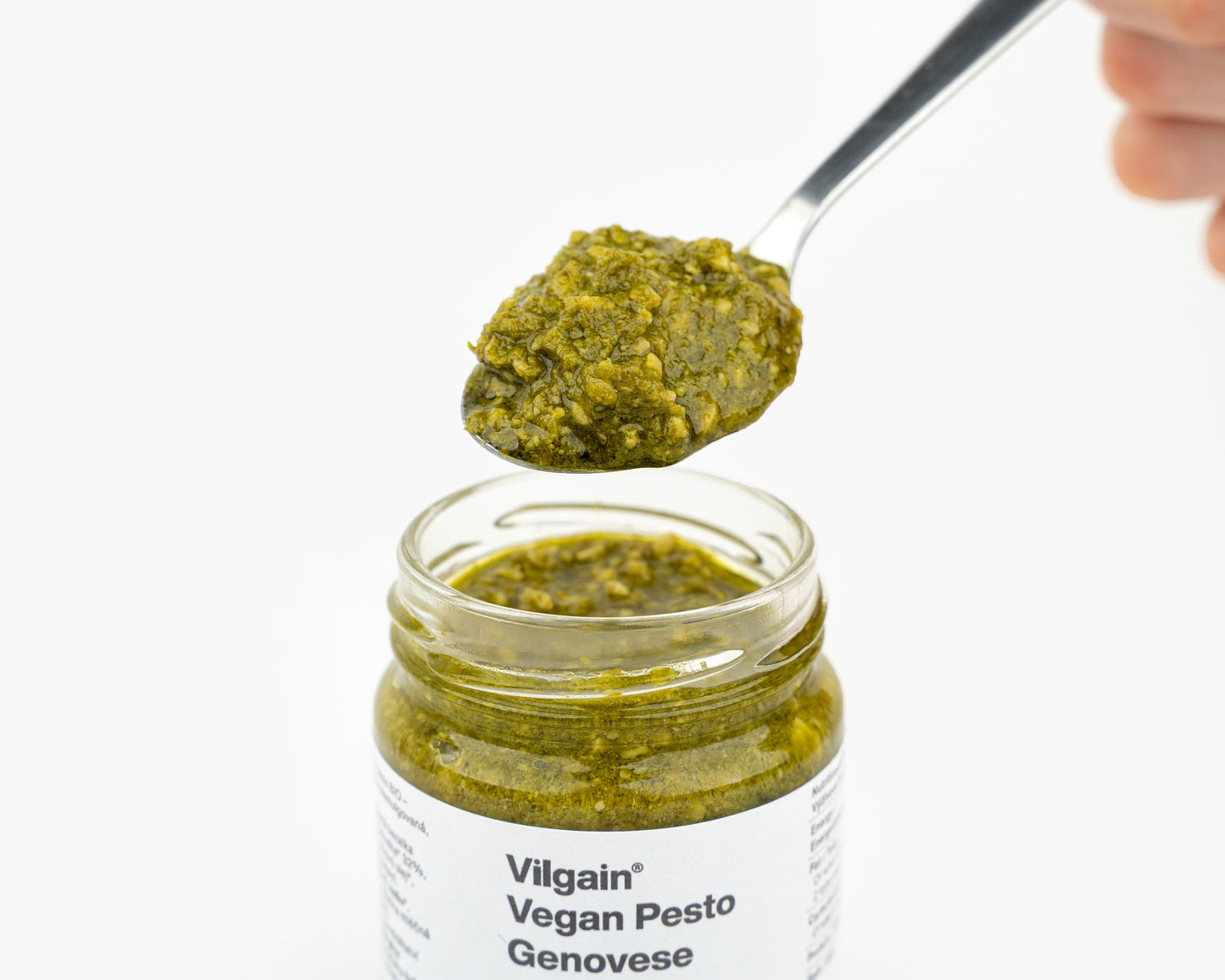 Kanálnyi Vilgain Vegán Pesto Genovese, amit egy üvegből merítenek, bemutatva a pesto élénkzöld színét és krémes állagát.