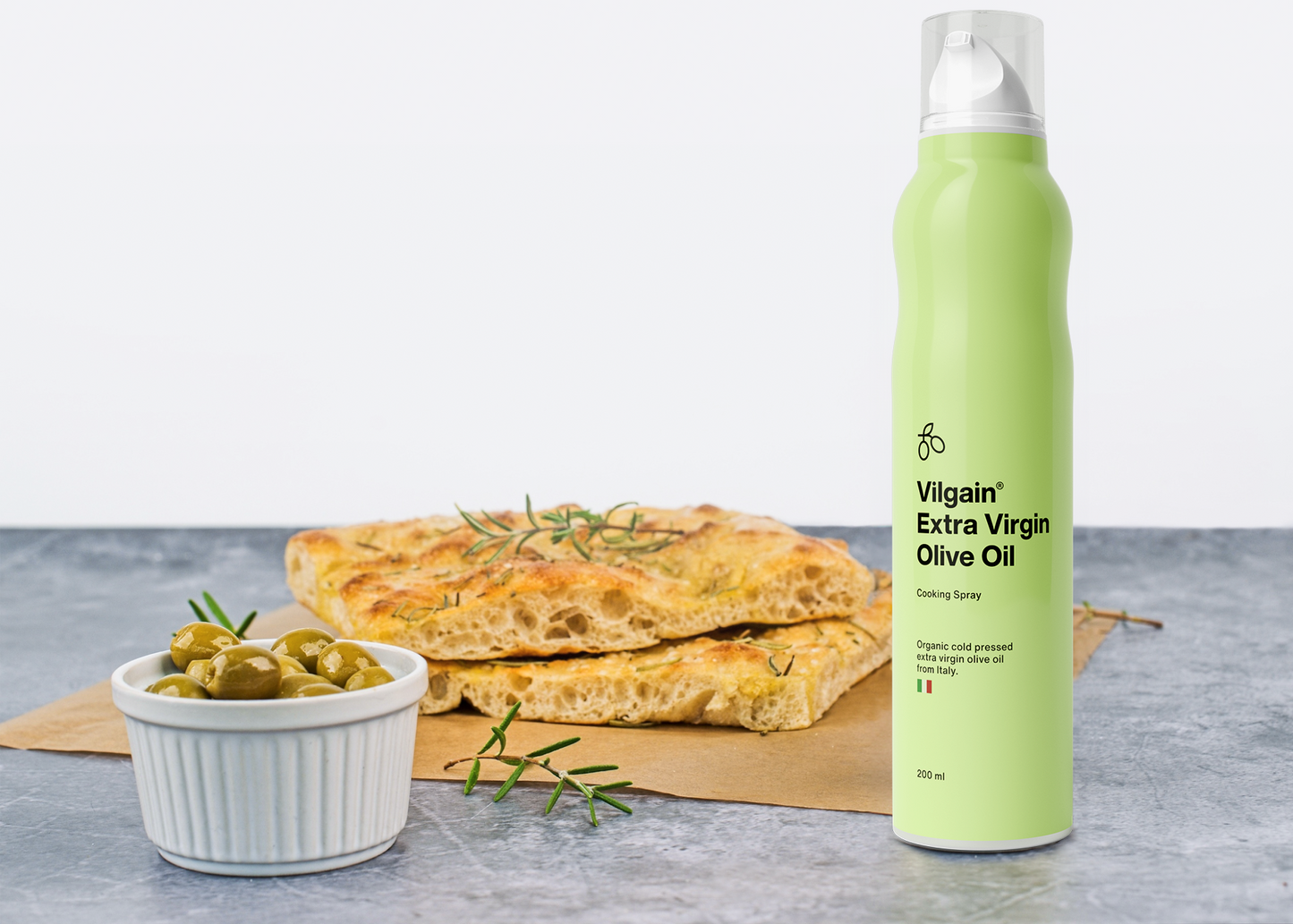 Vilgain BIO Olívaolaj spray és friss focaccia kenyér egy tányér olajbogyóval.